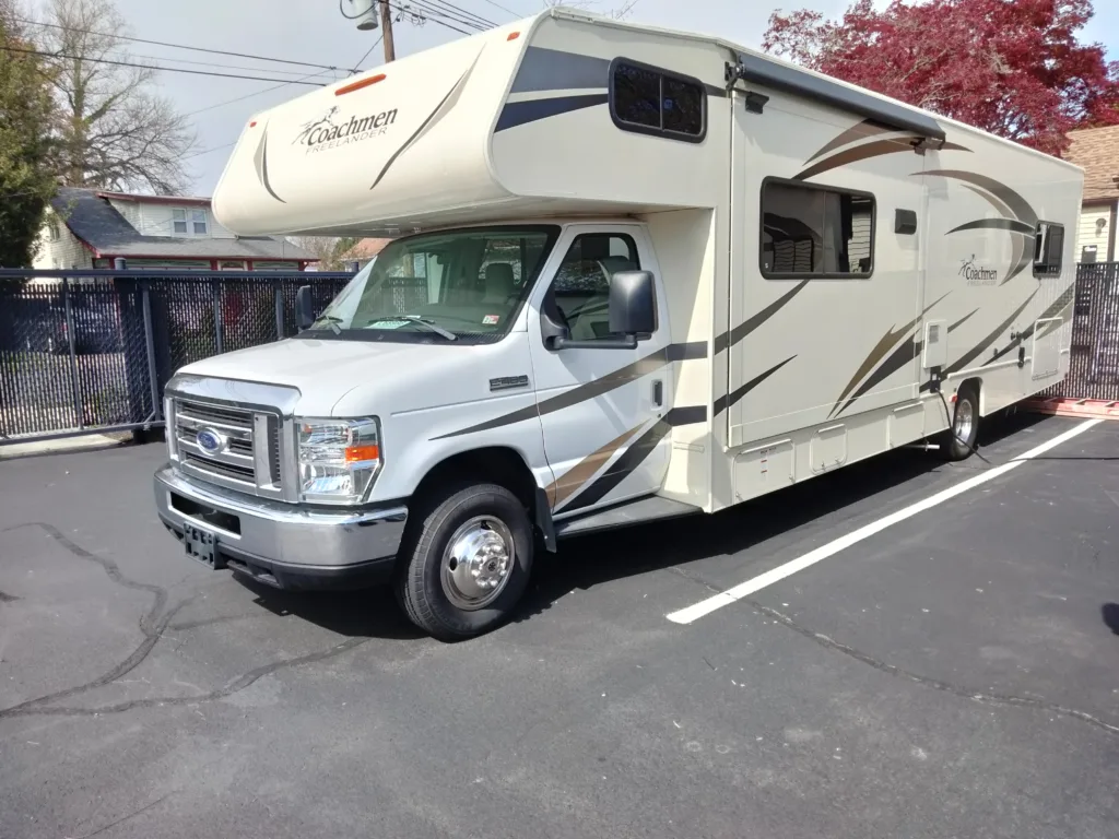 Image of a tan RV with blue and dark brown stripes. The RV is a 2018 Coachmen Freelander 31 BH Class C Motorhome.