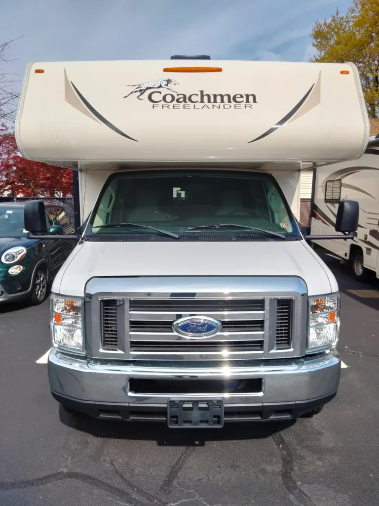 Image of a tan RV with blue and dark brown stripes. The RV is a 2018 Coachmen Freelander 31 BH Class C Motorhome.
